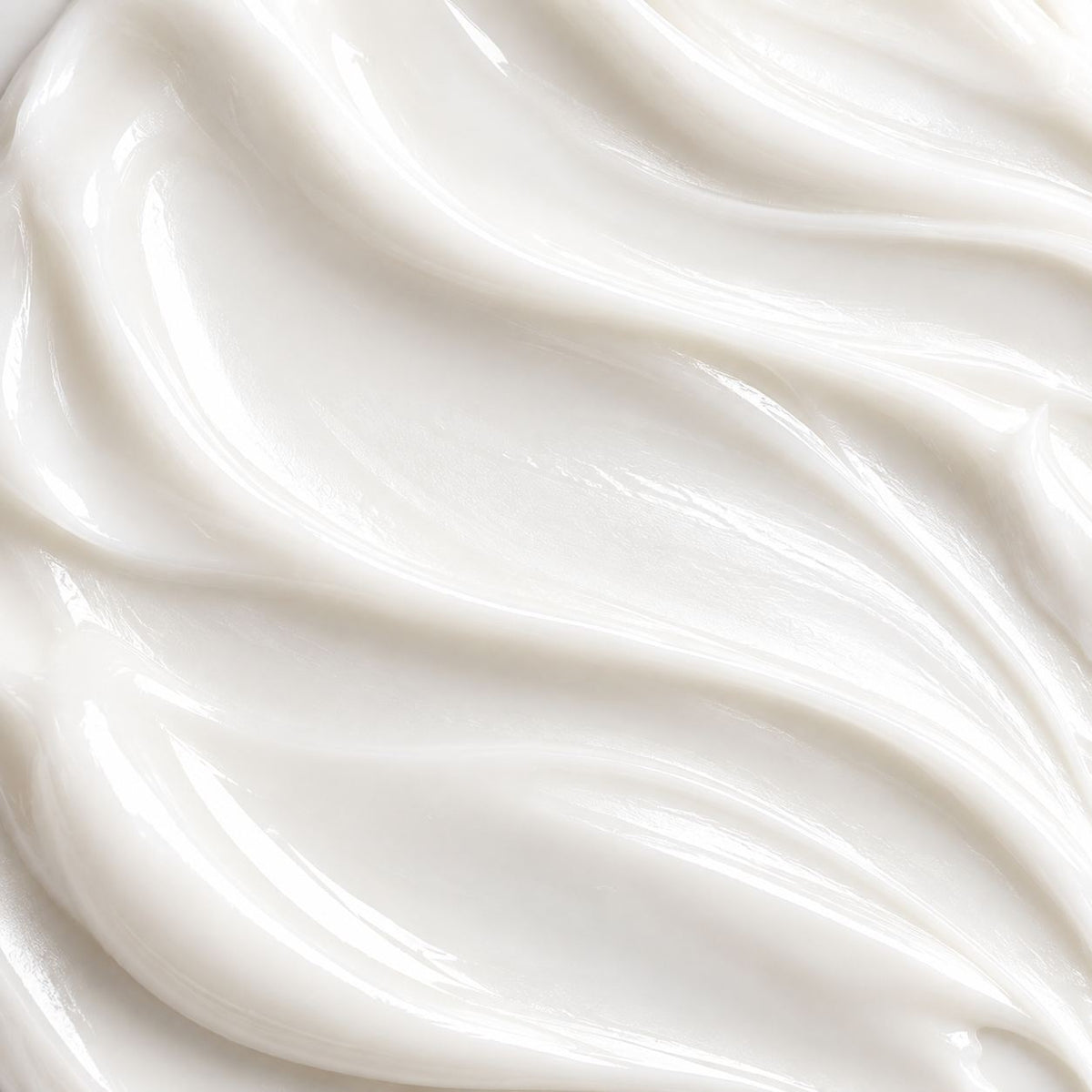 A close-up texture shot of a thick, creamy white cosmetic cream with smooth, flowing swirls and soft highlights.