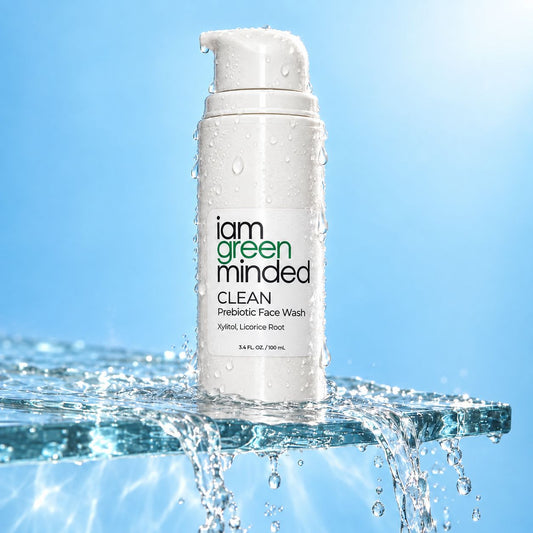 A white pump bottle of iam green minded Clean Prebiotic Face Wash standing in splashing water against a bright blue background.